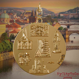 Halskette mit Drehwirbel und Rückseite eines vergoldeten Schmuckanhängers, auf dem Reliefs bekannter Sehenswürdigkeiten der Stadt Prag abgebildet sind. Den Hintergrund bildet eine Ansicht der Stadt Prag.
