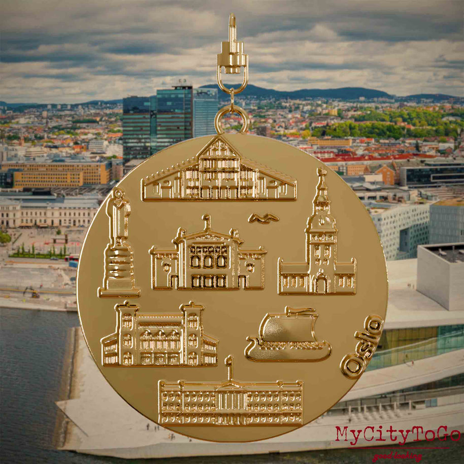 Halskette mit Drehwirbel und Rückseite eines vergoldeten Schmuckanhängers, auf dem Reliefs bekannter Sehenswürdigkeiten der Stadt Oslo abgebildet sind. Den Hintergrund bildet eine Ansicht der Stadt Oslo.
