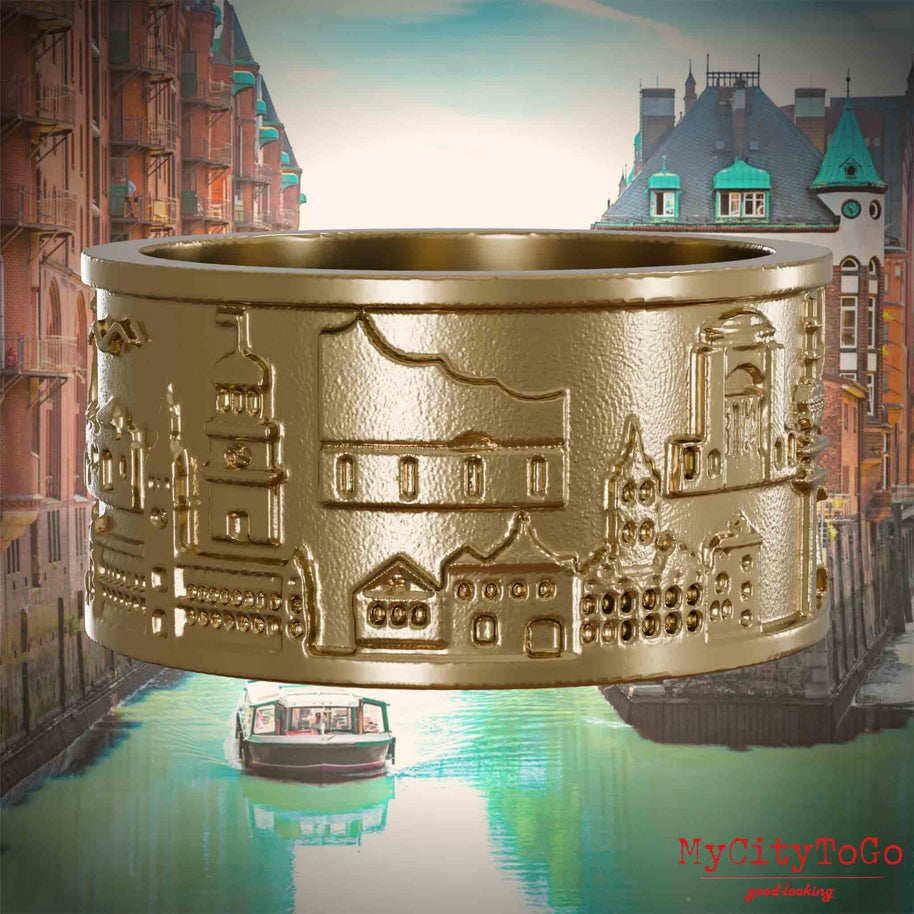 Ring aus vergoldetem Edelstahl mit Reliefs bekannter Sehenswürdigkeiten der Stadt Hamburg. Den Hintergrund bildet eine Ansicht der Stadt Hamburg.