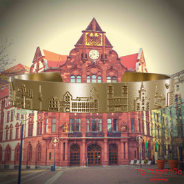 Armreif aus vergoldetem Edelstahl mit Reliefs bekannter Sehenswürdigkeiten der Stadt Dortmund. Den Hintergrund bildet eine Ansicht der Stadt Dortmund.