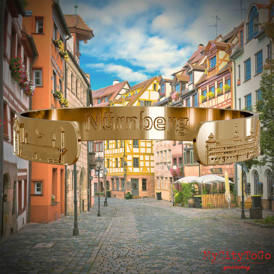 Innenseite eines silbernen Armreifs mit Reliefs bekannter Sehenswürdigkeiten der Stadt Nürnberg und einenr Gravur des Stadtnamens. Den Hintergrund bildet eine Ansicht der Stadt  Nuernberg.