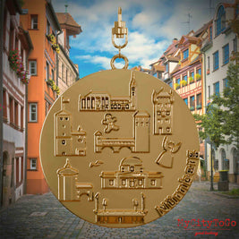 Halskette mit Drehwirbel und Rückseite eines vergoldeten Schmuckanhängers, auf dem Reliefs bekannter Sehenswürdigkeiten der Stadt Nuernberg abgebildet sind. Den Hintergrund bildet eine Ansicht der Stadt Nuernberg.