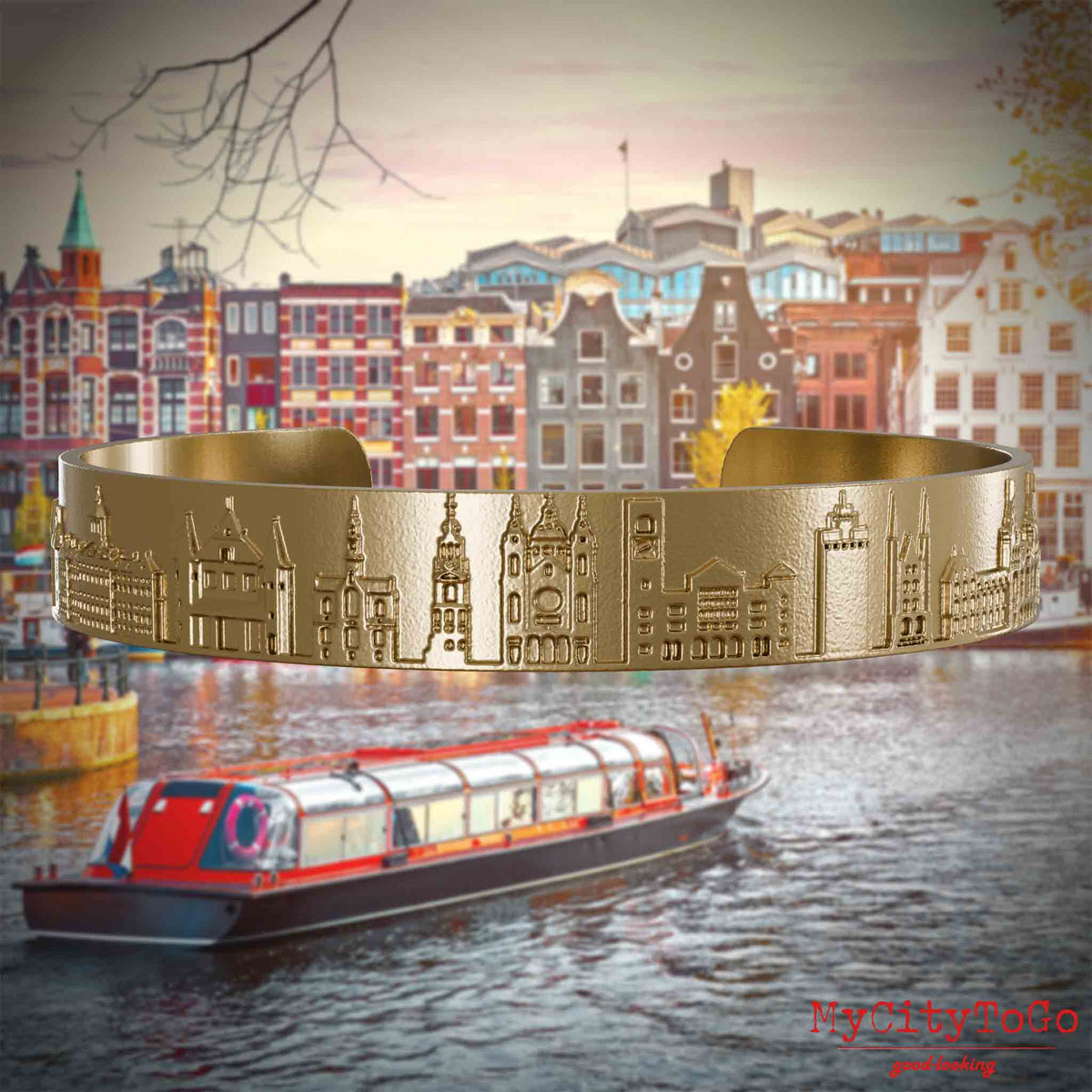 Armreif aus vergoldetem Edelstahl mit Reliefs bekannter Sehenswürdigkeiten der Stadt Amsterdam. Den Hintergrund bildet eine Ansicht der Stadt Amsterdam.