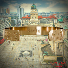 Innenseite eines Armreifs aus Edelstahl mit Reliefs bekannter Sehenswürdigkeiten der Stadt Berlin und einer Gravur des Stadtnamens. Den Hintergrund bildet eine Ansicht der Stadt Berlin. 