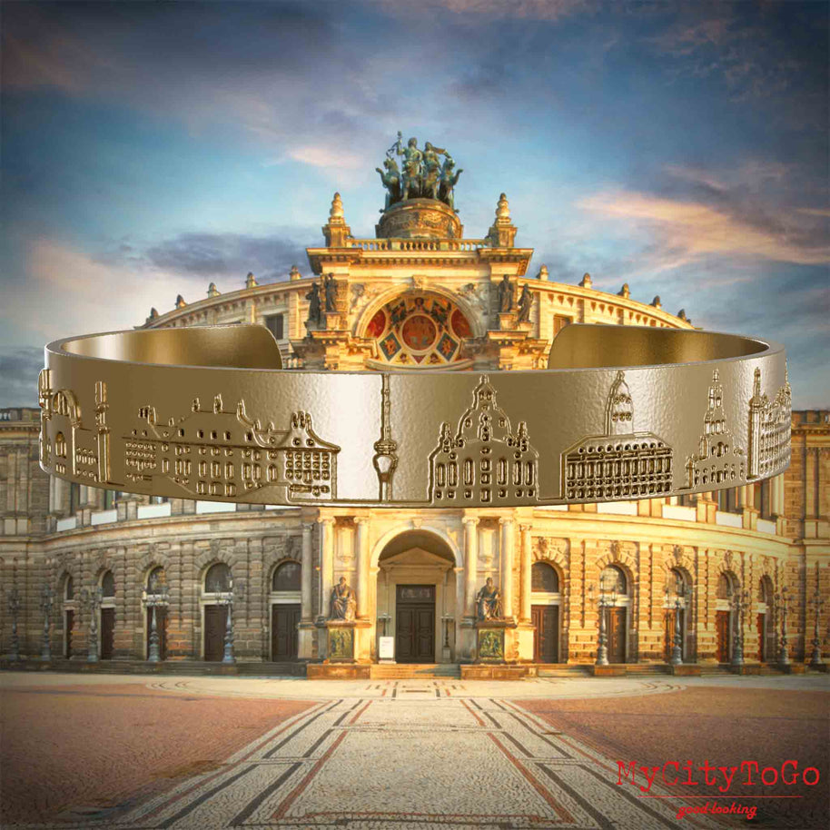 Vergoldeter Armreif aus Edelstahl mit Reliefs bekannter Sehenswürdigkeiten der Stadt Dresden. Den Hintergrund bildet eine Ansicht der Stadt Dresden.