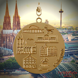 Halskette mit Drehwirbel und Vorderseite eines vergoldeten Schmuckanhängers, auf dem Reliefs bekannter Sehenswürdigkeiten der Stadt Koeln abgebildet sind. Den Hintergrund bildet eine Ansicht der Stadt Koeln.