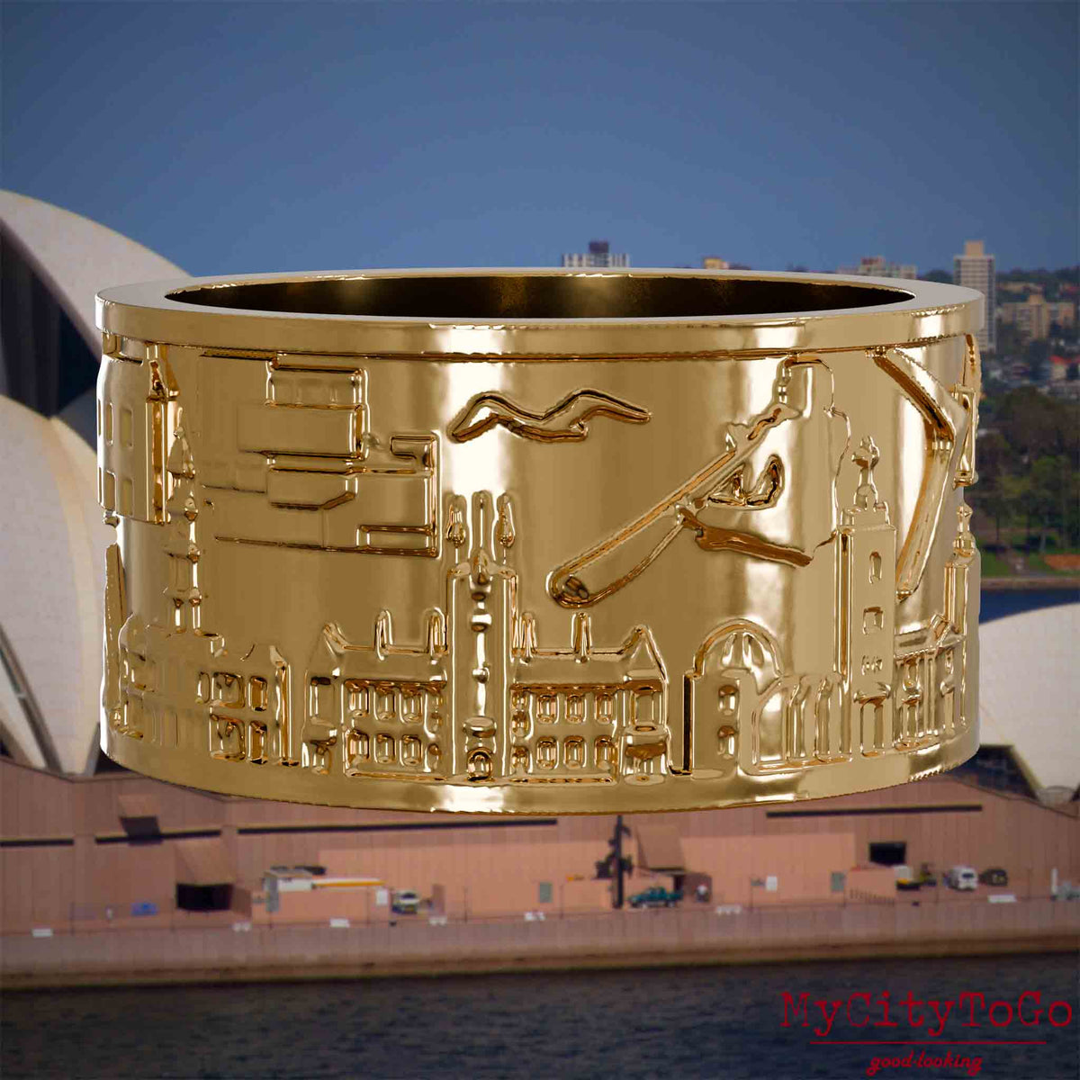 Vergoldeter Ring mit Reliefs bekannter Sehenswürdigkeiten der Stadt Sydney. Den Hintergrund bildet eine Ansicht der Stadt Sydney.
