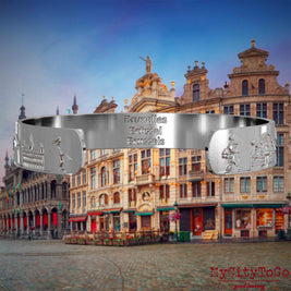 Innenseite eines silbernen Armreifs mit Reliefs bekannter Sehenswürdigkeiten der Stadt Brüssel und einer Gravur des Stadtnamens. Den Hintergrund bildet eine Ansicht der Stadt Bruessel.