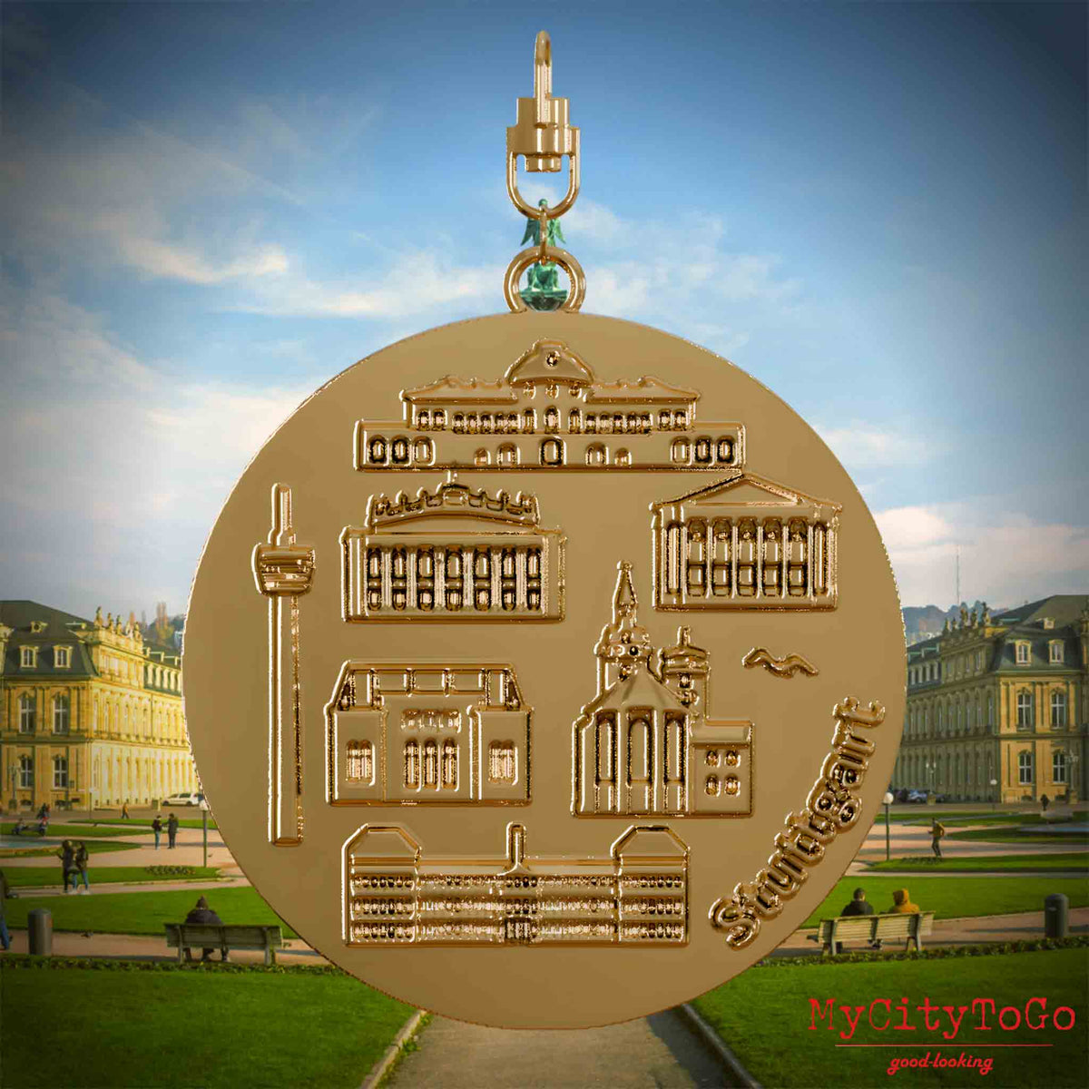 Halskette mit Drehwirbel und Vorderseite eines vergoldeten Schmuckanhängers, auf dem Reliefs bekannter Sehenswürdigkeiten der Stadt Stuttgart abgebildet sind. Den Hintergrund bildet eine Ansicht der Stadt Stuttgart.
