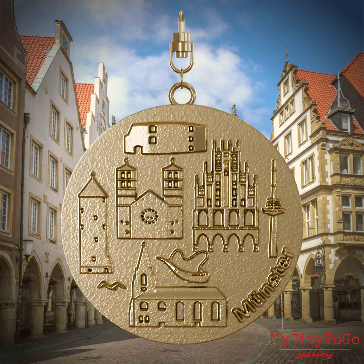 Halskette mit Drehwirbel und Vorderseite eines Schmuckanhängers aus vergoldetem Edelstahl, auf dem Reliefs bekannter Sehenswürdigkeiten der Stadt Muenster abgebildet sind. Den Hintergrund bildet eine Ansicht der Stadt Muenster.