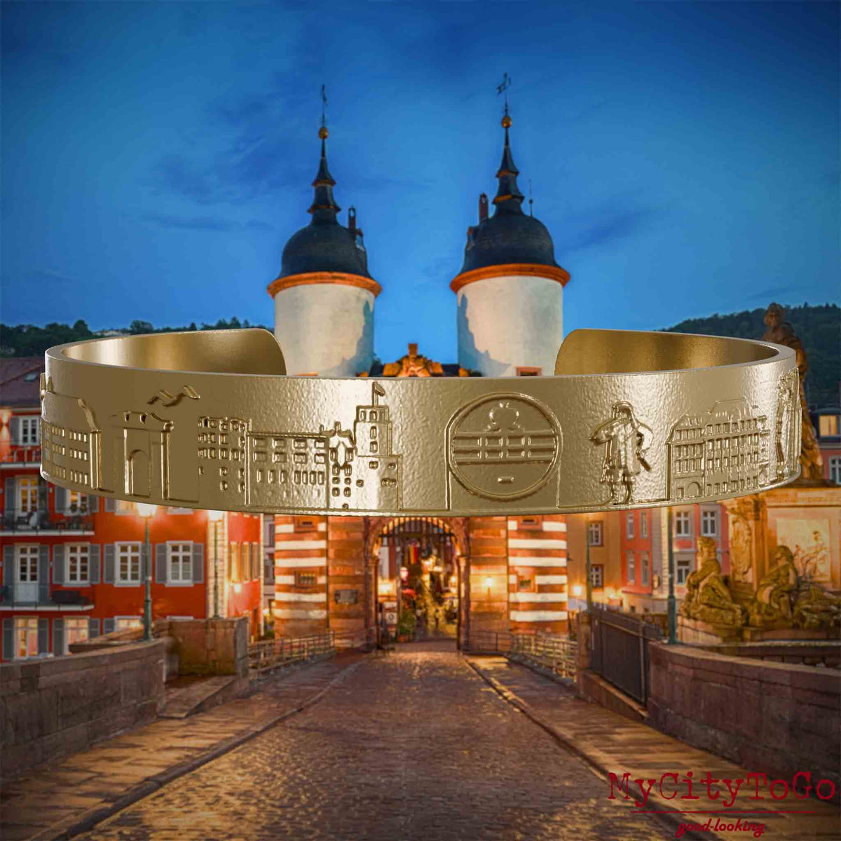 Armreif aus vergoldetem Edelstahl mit Reliefs bekannter Sehenswürdigkeiten der Stadt Heidelberg. Den Hintergrund bildet eine Ansicht der Stadt Heidelberg.