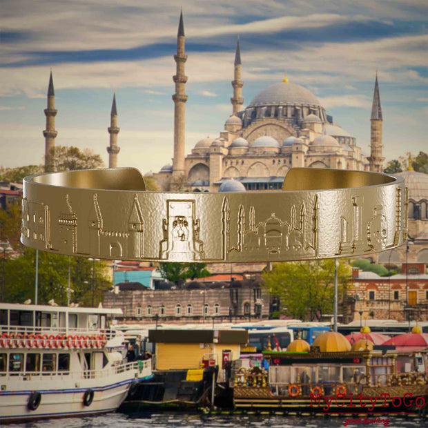 Armreif aus vergoldetem Edelstahl mit Reliefs bekannter Sehenswürdigkeiten der Stadt Istanbul. Den Hintergrund bildet eine Ansicht der Satdt Istanbul.