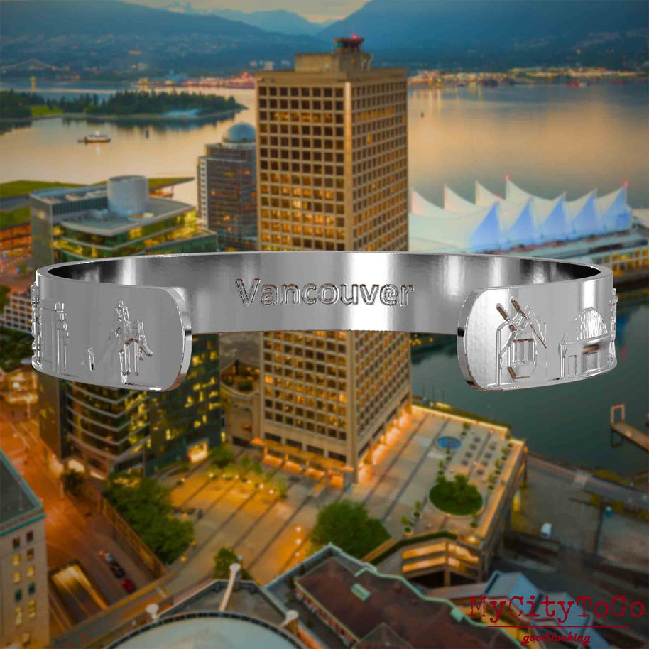 Innenseite eines silbernen Armreifs mit Reliefs bekannter Sehenswürdigkeiten der Stadt Vancouver und einer Gravur des Stadtnamens. Den Hintergrund bildet eine Ansicht der Stadt Vancouver.