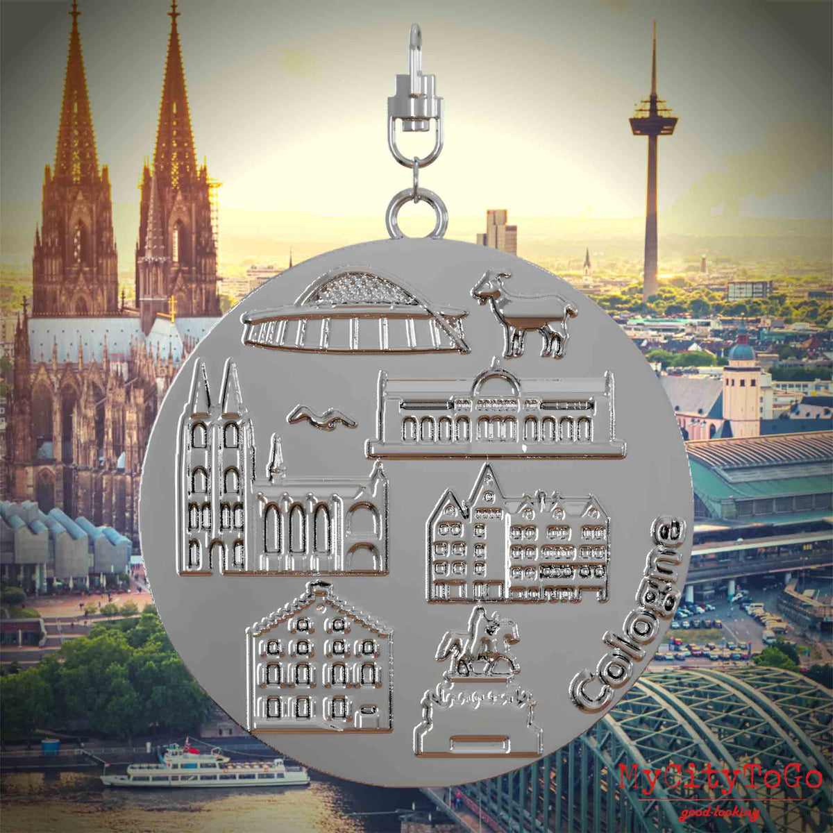 Halskette mit Drehwirbel und Vorderseite eines silbernen Schmuckanhängers, auf dem Reliefs bekannter Sehenswürdigkeiten der Stadt Koeln abgebildet sind. Den Hintergrund bildet eine Ansicht der Stadt Koeln.