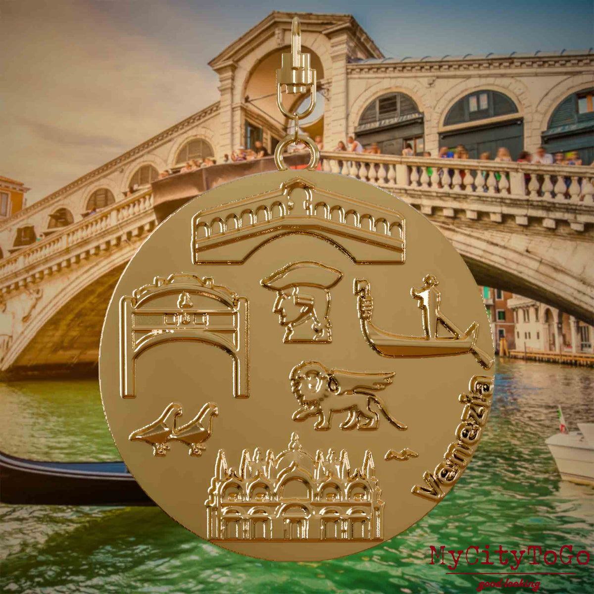 Halskette mit Drehwirbel und Vorderseite eines vergoldeten Schmuckanhängers, auf dem Reliefs bekannter Sehenswürdigkeiten der Stadt Venedig abgebildet sind. Den Hintergrund bildet eine Ansicht der Stadt Venedig.
