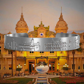 Armreif aus Edelstahl mit Reliefs bekannter Sehenswürdigkeiten der Stadt Monte Carlo. Den Hintergrund bildet eine Ansicht der Stadt Monte Carlo.