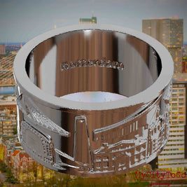 Versilberter Ring mit Reliefs bekannter Sehenswürdigkeiten der Stadt Rotterdam und einer Gravur des Stadtnamens auf der Innenseite. Den Hintergrund bildet eine Ansicht der Stadt Rotterdam.