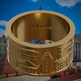 Ring aus vergoldetem Edelstahl mit Reliefs bekannter Sehenswürdigkeiten der Stadt Karlsruhe und einer Gravur des Stadtnamens auf der Innenseite. Den Hintergrund bildet eine Ansicht der Stadt Karlsruhe.