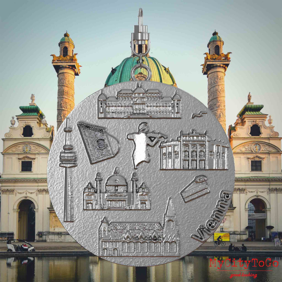 Halskette mit Drehwirbel und Rückseite eines Schmuckanhängers aus Edelstahl, auf dem Reliefs bekannter Sehenswürdigkeiten der Stadt Wien abgebildet sind. Den Hintergrund bildet eine Ansicht der Stadt Wien.
