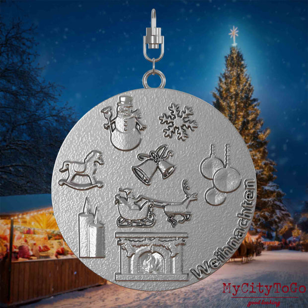 Halskette mit Drehwirbel und Vorderseite eines Schmuckanhängers aus Edelstahl, auf dem Reliefs bekannter Weihnachst- und Wintermotive abgebildet sind. Den Hintergrund bildet ein naechtliches Weihnachtsmotiv.
