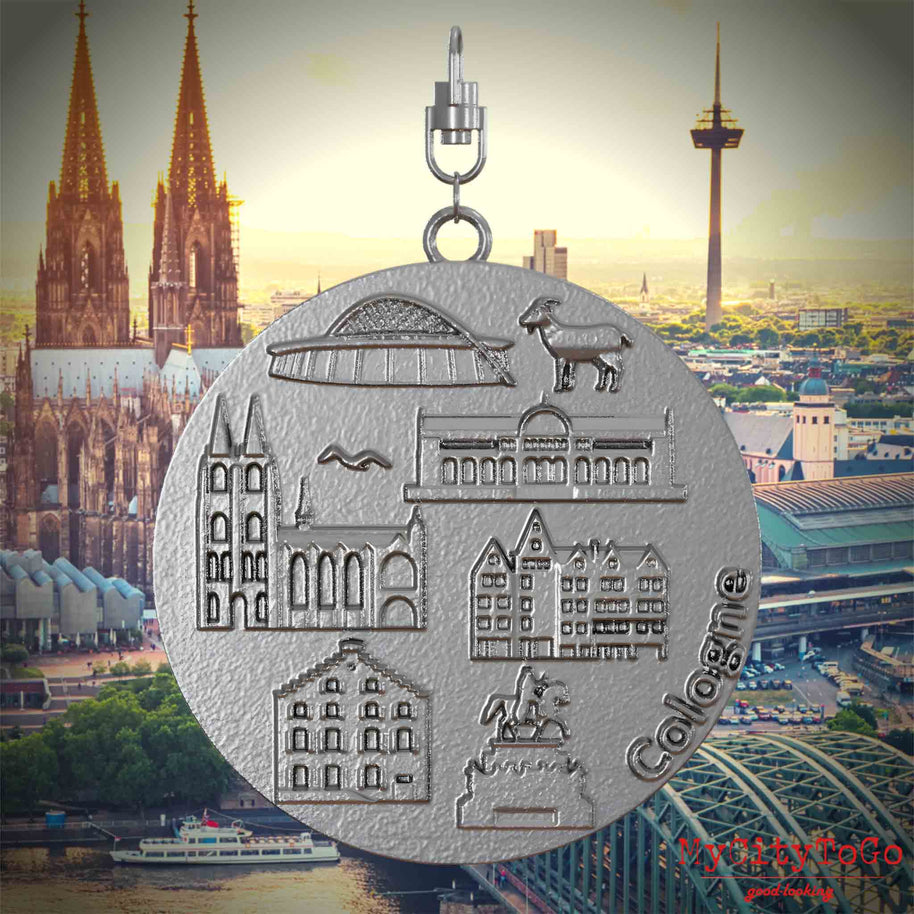 Halskette mit Drehwirbel und Vorderseite eines Schmuckanhängers aus Edelstahl, auf dem Reliefs bekannter Sehenswürdigkeiten der Stadt Koeln abgebildet sind. Den Hintergrund bildet eine Ansicht der Stadt Koeln.
