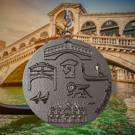 Halskette mit Drehwirbel und Vorderseite eines Schmuckanhängers aus Titan, auf dem Reliefs bekannter Sehenswürdigkeiten der Stadt Venedig abgebildet sind. Den Hintergrund bildet eine Ansicht der Stadt Venedig.
