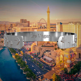 Innenseite eines silbernen Armreifs mit Reliefs bekannter Sehenswürdigkeiten der Stadt Las Vegas und einer Gravur des Stadtnamens. Den Hintergrund bildet eine Ansicht der Stadt Las Vegas.