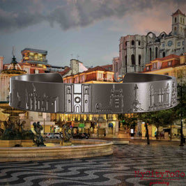 Armreif aus Titan mit Reliefs bekannter Sehenswürdigkeiten von Lissabon. Den Hintergrund bildet eine Ansicht der Stadt Lissabon.