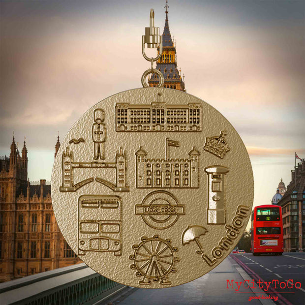 Halskette mit Drehwirbel und Vorderseite eines Schmuckanhängers aus vergoldetem Edelstahl, auf dem Reliefs bekannter Sehenswürdigkeiten der Stadt London abgebildet sind. Den Hintergrund bildet eine Ansicht der Stadt London. 
