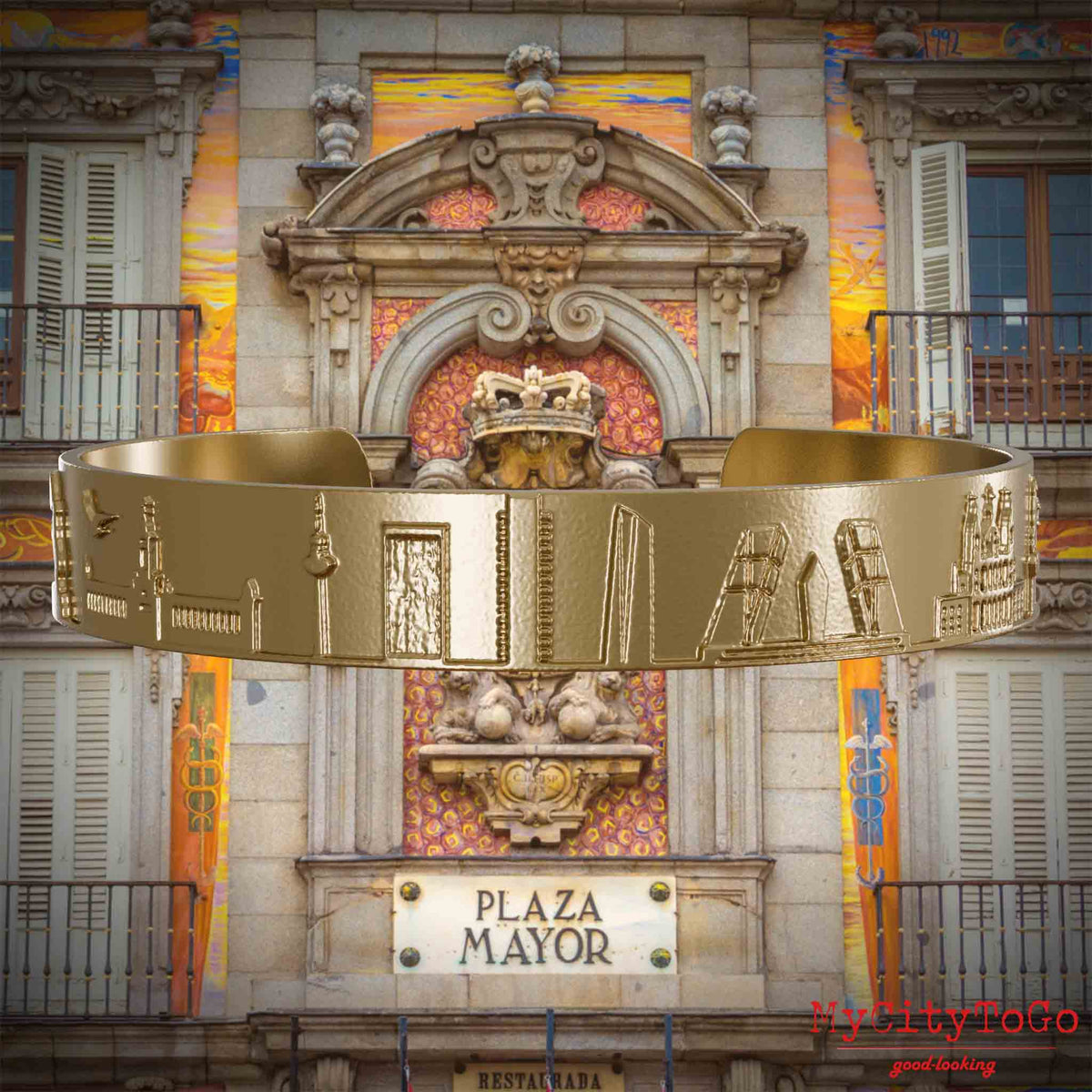 Armreif aus vergoldetem Edelstahl mit Reliefs bekannter Sehenswürdigkeiten der Stadt Madrid. Den Hintergrund bildet eine Ansicht der Stadt Madrid.