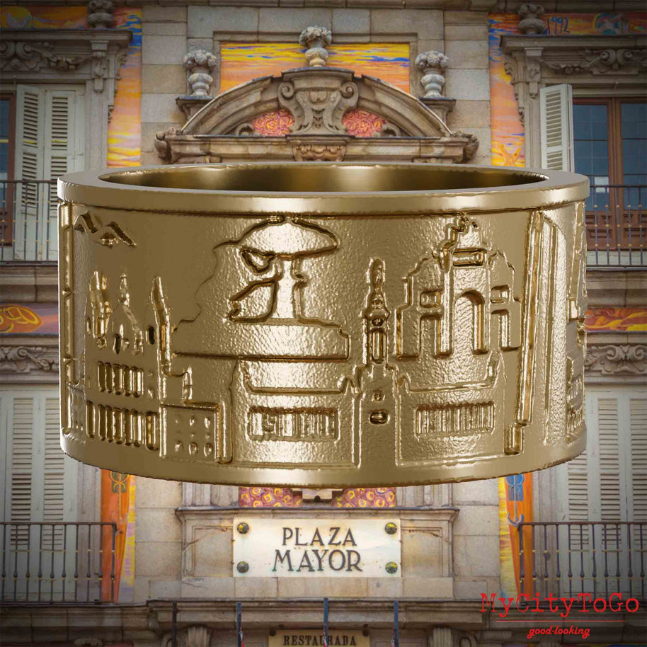 Ring aus vergoldetem Edelstahl mit Reliefs bekannter Sehenswürdigkeiten der Stadt Madrid. Den Hintergrund bildet eine Ansicht der Stadt Madrid.