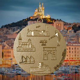 Halskette mit Drehwirbel und Vorderseite eines Schmuckanhängers aus vergoldetem Edelstahl, auf dem Reliefs bekannter Sehenswürdigkeiten der Stadt Marseille abgebildet sind. Den Hintergrund bildet eine Ansicht der Stadt Marseille.
