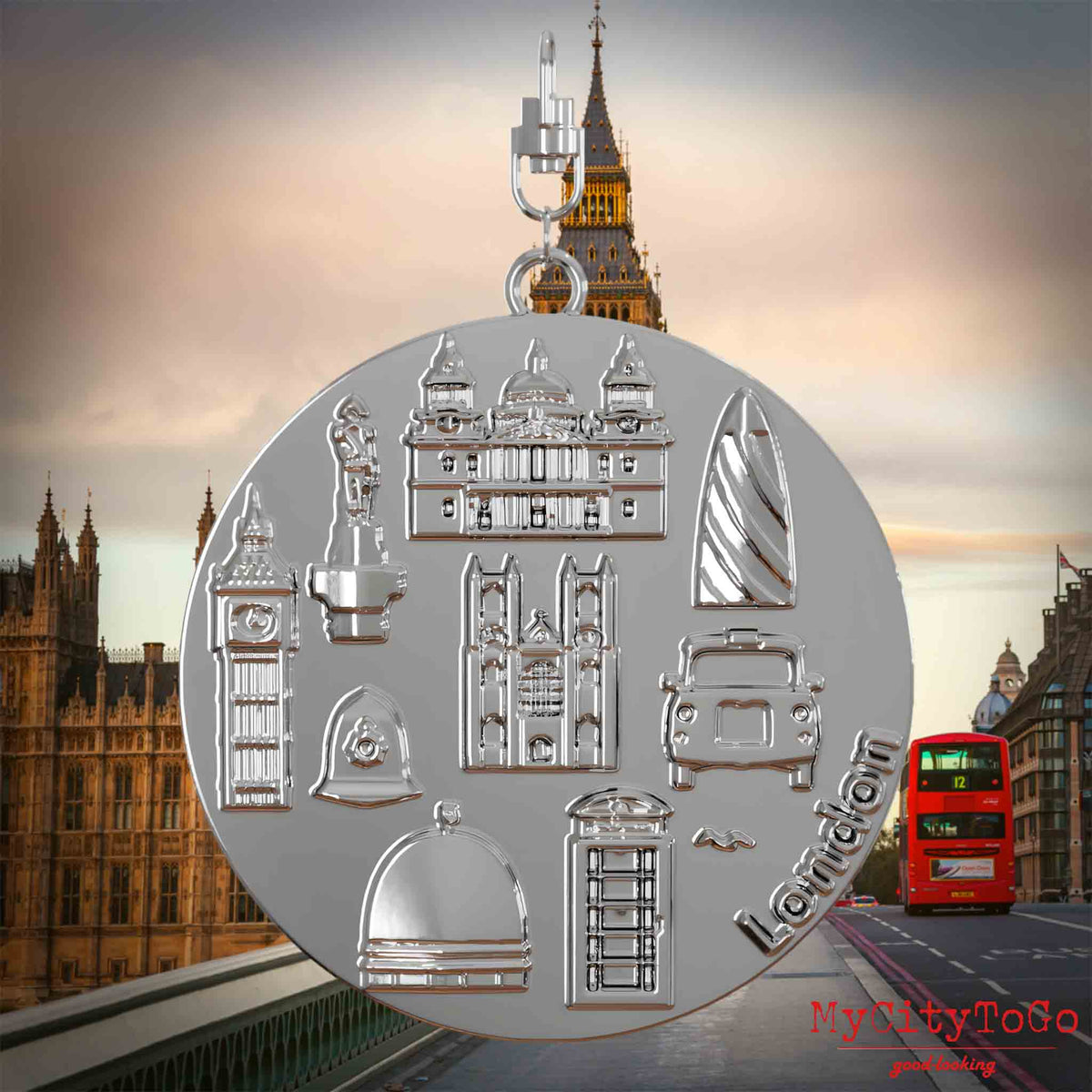 Halskette mit Drehwirbel und Rückseite eines silbernen Schmuckanhängers, auf dem Reliefs bekannter Sehenswürdigkeiten der Stadt London abgebildet sind. Den Hintergrund bildet eine Ansicht der Stadt London.
