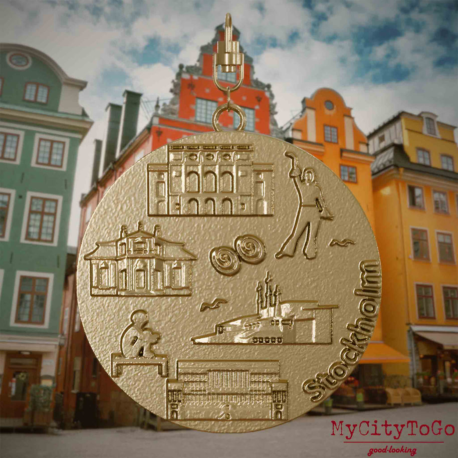 Halskette mit Drehwirbel und Vorderseite eines Schmuckanhängers aus vergoldetem Edelstahl, auf dem Reliefs bekannter Sehenswürdigkeiten der Stadt Stockholm abgebildet sind. Den Hintergrund bildet eine Ansicht der Stadt Stockholm. 

