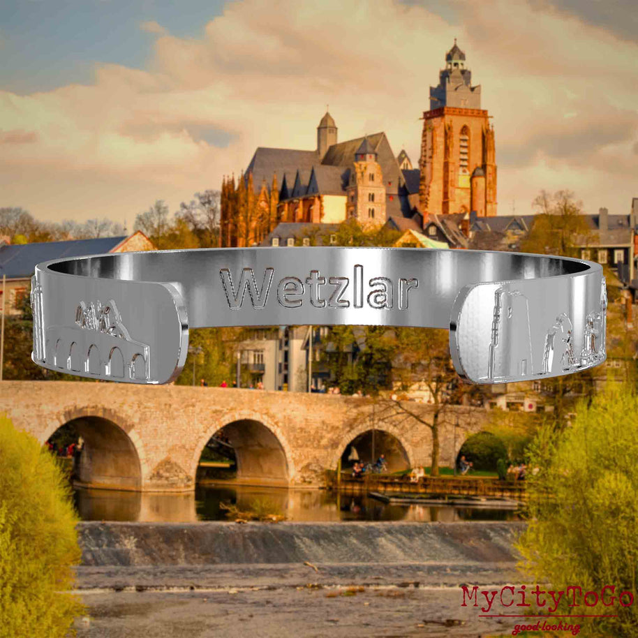 Innenseite eines silbernen Armreifs mit Reliefs bekannter Sehenswürdigkeiten der Stadt Wetzlar und einer Gravur des Stadtnamens. Den Hintergrund bildet eine Ansicht der Stadt Wetzlar.