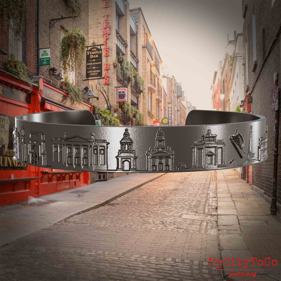 Armreif aus Titan mit Reliefs bekannter Sehenswürdigkeiten der  Stadt Dublin. Den Hintergrund bildet eine Ansicht der Stadt Dublin.