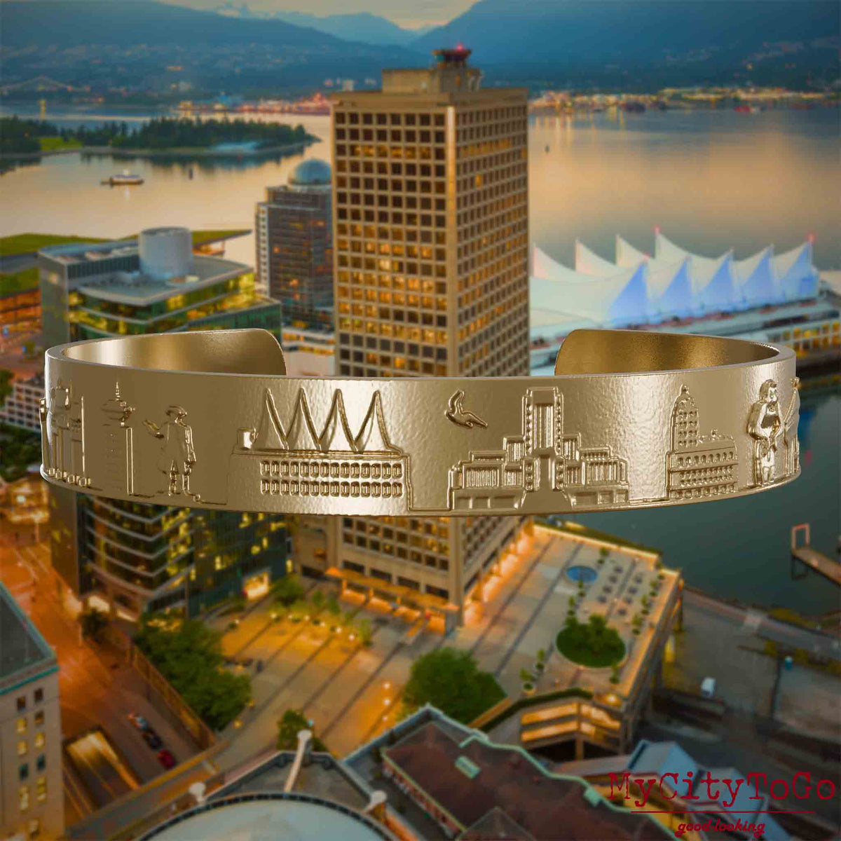 Armreif aus vergoldetem Edelstahl mit Reliefs bekannter Sehenswürdigkeiten der Stadt Vancouver. Den Hintergrund bildet eine Ansicht der Stadt Vancouver.