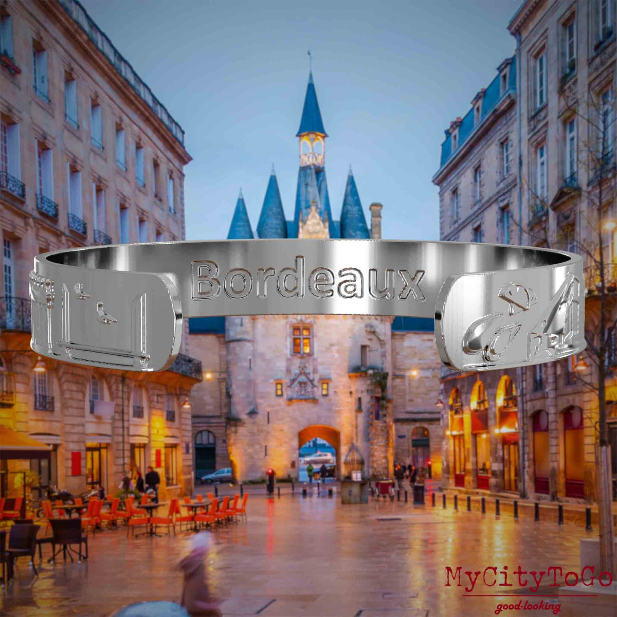 Innenseite eines silbernen Armreifs mit Reliefs bekannter Sehenswürdigkeiten der Stadt Bordeaux und einer Gravur des Stadtnamens. Den Hintergrund bildet eine Ansicht der Stadt Bordeaux.