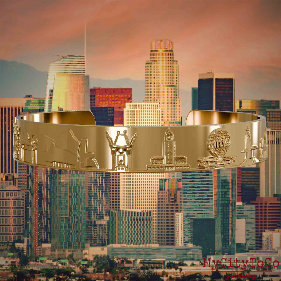 Vergoldeter Armreif mit Reliefs bekannter Sehenswürdigkeiten der Stadt Los Angeles. Den Hintergrund bildet eine Ansicht der Stadt Los Angeles.