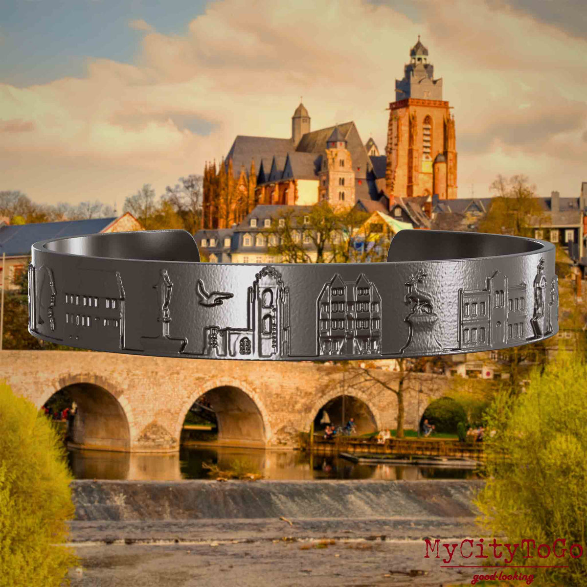 Armreif aus Titan mit Reliefs bekannter Sehenswürdigkeiten der Stadt Wetzlar. Den Hintergrund bildet eine Ansicht der Stadt Wetzlar.