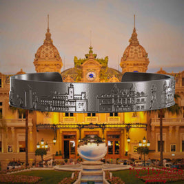 Armreif aus Titan mit Reliefs bekannter Sehenswürdigkeiten der Stadt Monte Carlo. Den Hintergrund bildet eine Ansicht der Stadt Monte Carlo.