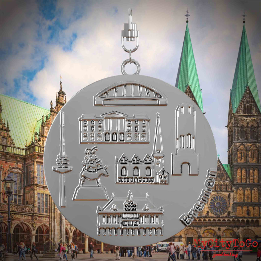 Halskette mit Drehwirbel und Vorderseite eines silbernen Schmuckanhängers, auf dem Reliefs bekannter Sehenswürdigkeiten der Stadt Bremen abgebildet sind. Den Hintergrund bildet eine Ansicht der Stadt Bremen.