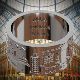 Versilberter Ring mit Reliefs bekannter Sehenswürdigkeiten der Stadt Mailand und einer Gravur des Stadtnamens auf der Innenseite. Den Hintergrund bildet eine Ansicht der Stadt Mailand.