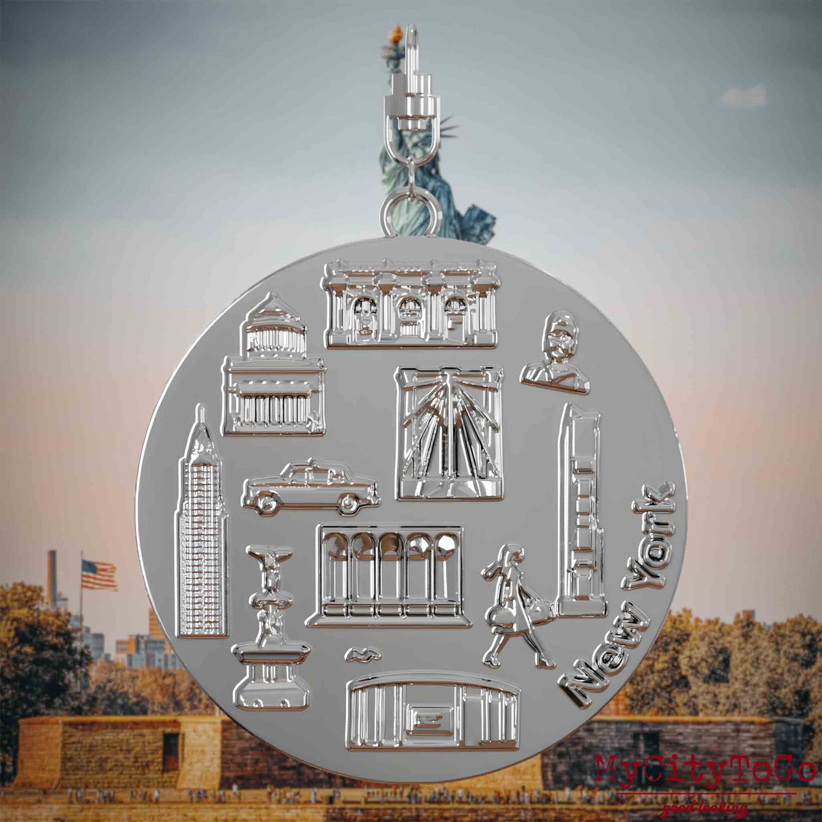Halskette mit Drehwirbel und Rückseite eines silbernen Schmuckanhängers, auf dem Reliefs bekannter Sehenswürdigkeiten der Stadt New York abgebildet sind. Den Hintergrund bildet eine Ansicht der Stadt New York.
