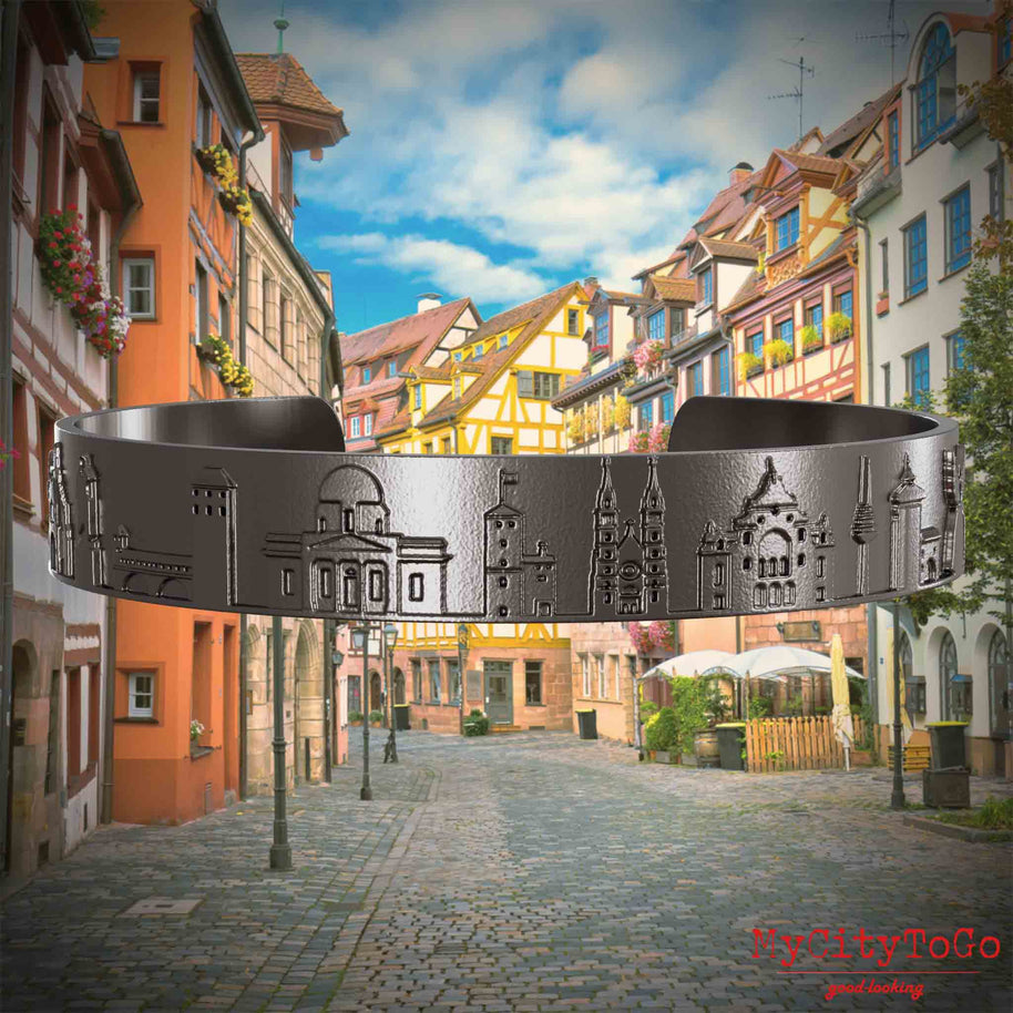 Armreif aus Titan mit Reliefs bekannter Sehenswürdigkeiten der Stadt Nürnberg. Den Hintergrund bildet eine Ansicht der Stadt  Nuernberg.