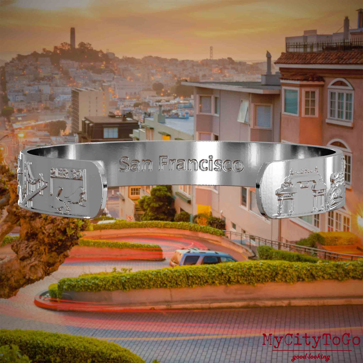 Innenseite eines silbernen Armreifs mit Reliefs bekannter Sehenswürdigkeiten der Stadt San Francisco und einer Gravur des Stadtnamens. Den Hintergrund bildet eine Ansicht der Stadt San Francisco.