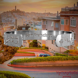 Innenseite eines silbernen Armreifs mit Reliefs bekannter Sehenswürdigkeiten der Stadt San Francisco und einer Gravur des Stadtnamens. Den Hintergrund bildet eine Ansicht der Stadt San Francisco.