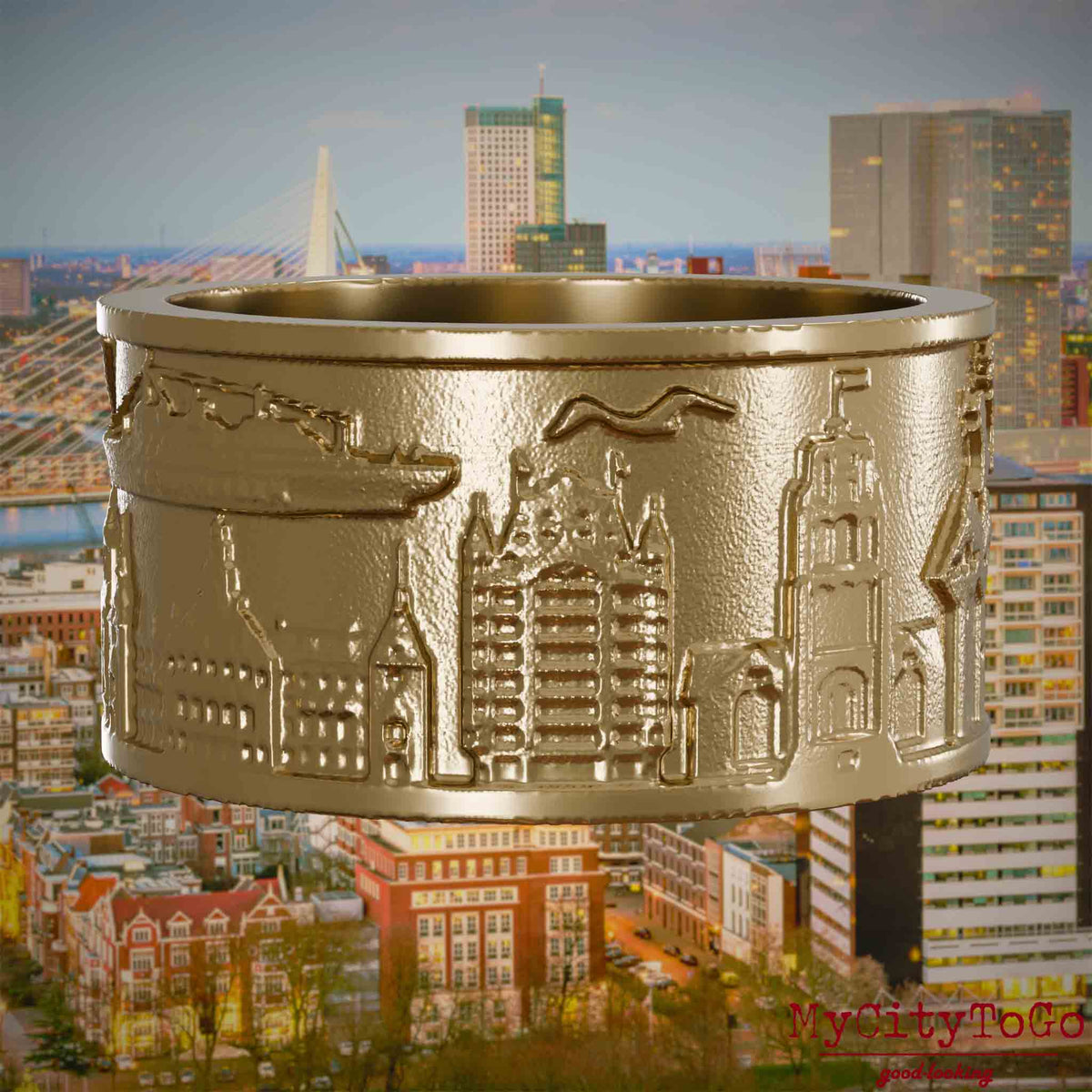 Ring aus vergoldetem Edelstahl mit Reliefs bekannter Sehenswürdigkeiten der Stadt Rotterdam. Den Hintergrund bildet eine Ansicht der Stadt Rotterdam.