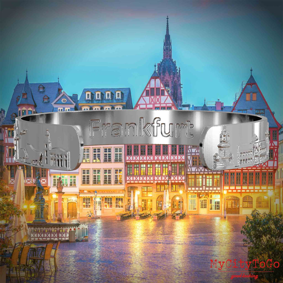 Innenseite eines silbernen Armreifs mit Reliefs bekannter Sehenswürdigkeiten der Stadt Frankfurt und einer Gravur des Stadtnamens. Den Hintergrund bildet eine Ansicht der Stadt Frankfurt.