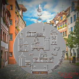 Halskette mit Drehwirbel und Rückseite eines silbernen Schmuckanhängers, auf dem Reliefs bekannter Sehenswürdigkeiten der Stadt Nürnberg abgebildet sind. Den Hintergrund bildet eine Ansicht der Stadt Nürnberg.